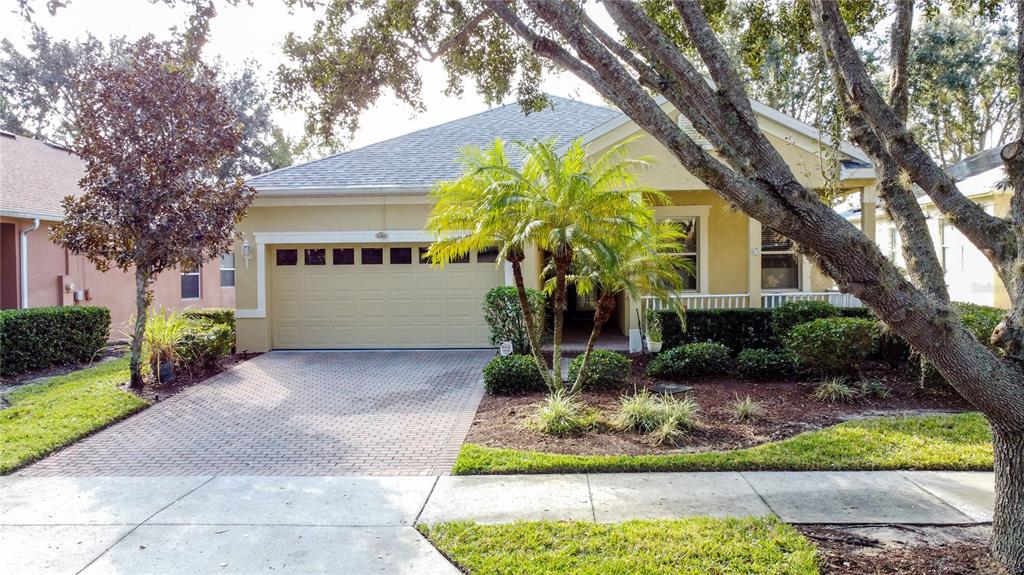 A single-story house with a tan exterior, a two-car garage, and a brick paver driveway — 146 CREPE MYRTLE DRIVE, GROVELAND, FL