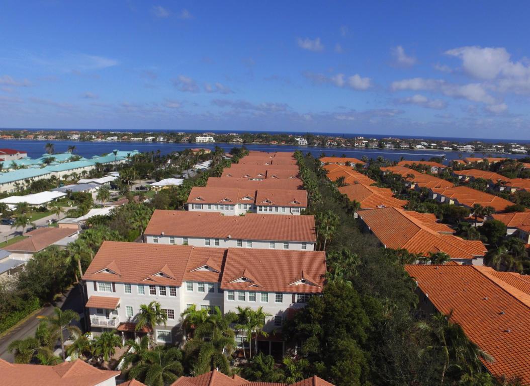 An aerial view shows multiple rows of townhouses with orange tile roofs near a waterway — 118 Ocean Cay Way, Hypoluxo FL 33462, HYPOLUXO, FL