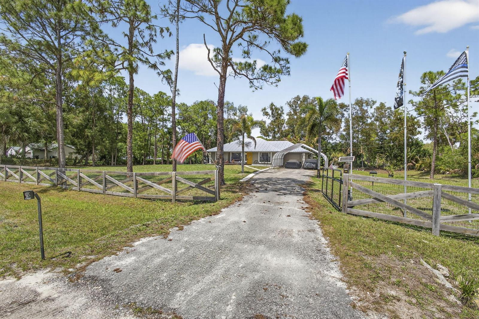 A gravel driveway leads to a single-story house with a metal roof and fenced yard — 17815 92nd Lane N, FL 33470, FL
