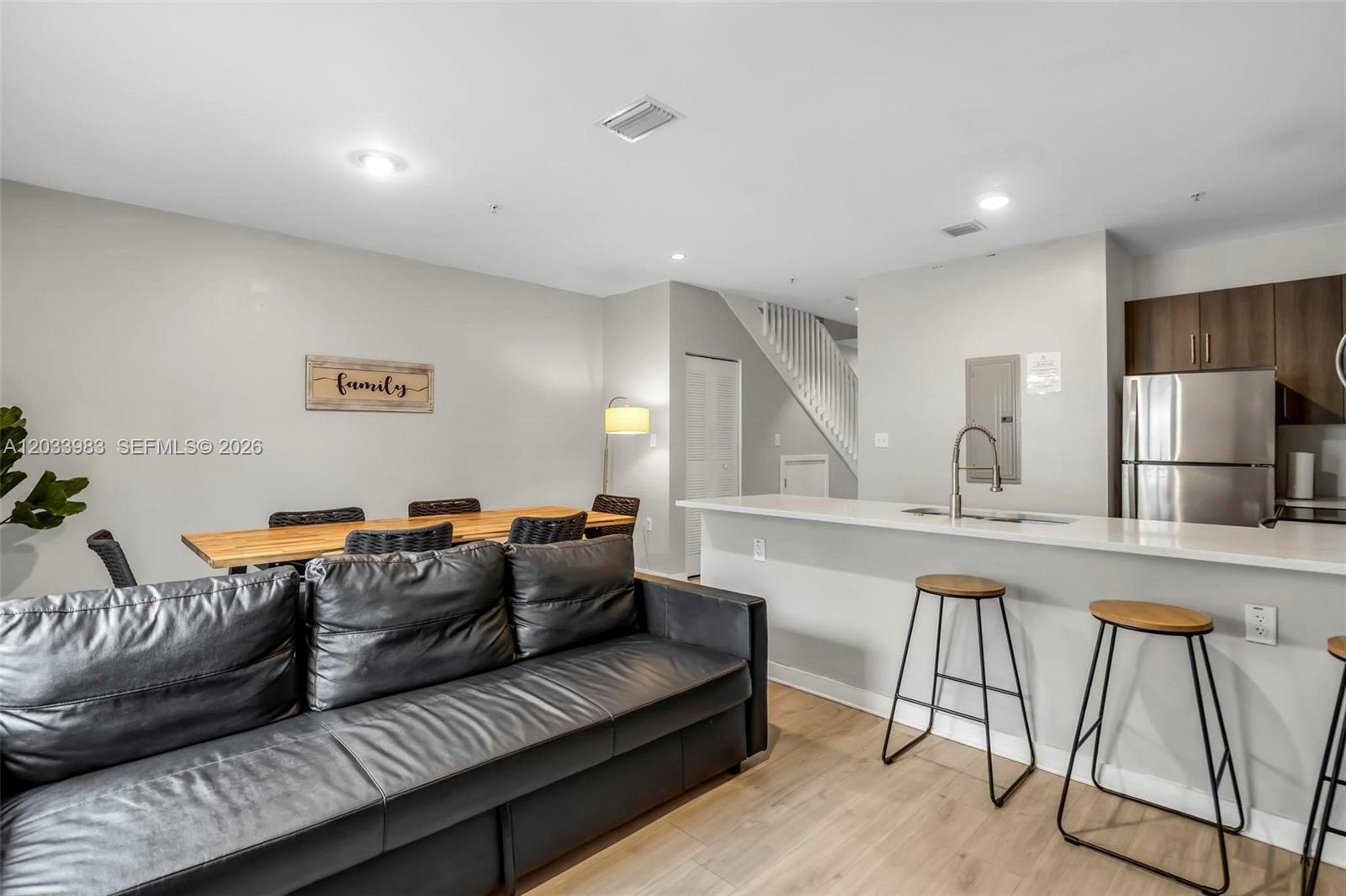 A living room and kitchen area feature a black leather sofa, dining table, and stools — 171 NW 158th St # 10, Miami FL 33169, MIAMI, FL
