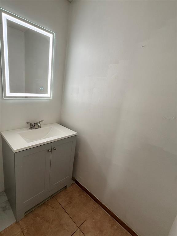 A bathroom features a gray vanity with a white sink and an illuminated wall mirror — 4113 S SEMORAN BOULEVARD UNIT 14, ORLANDO, FL