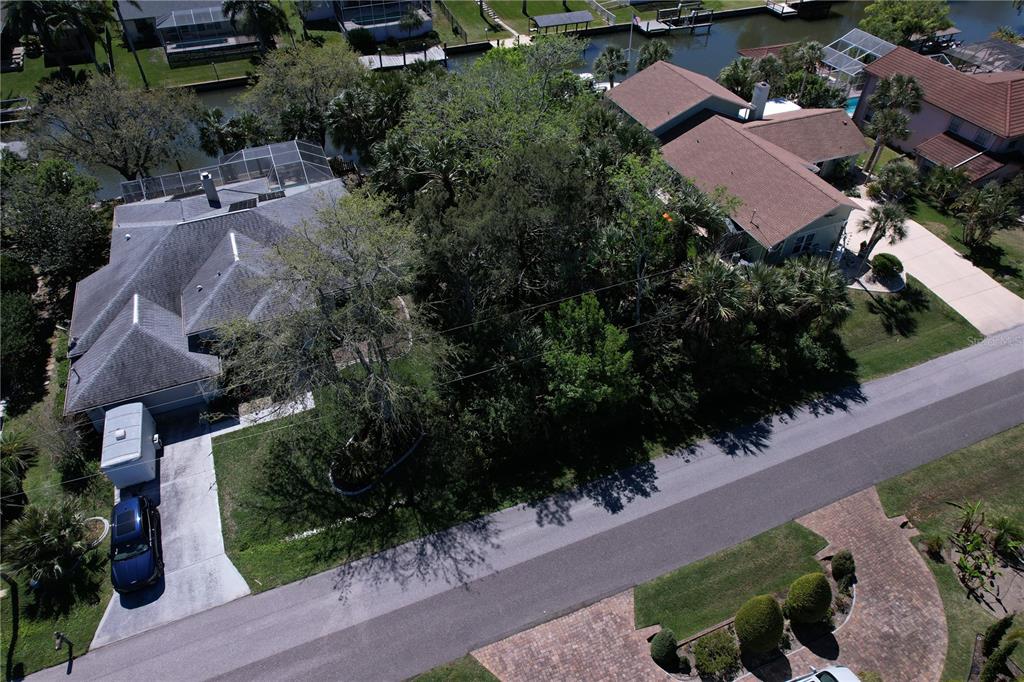An aerial view shows two houses separated by a wooded lot along a canal — 25 CHEROKEE COURT W, PALM COAST, FL