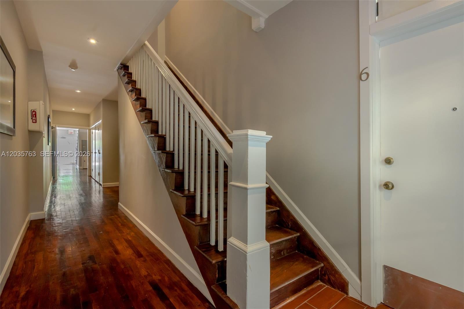 A wooden staircase with white railings sits in a hallway with hardwood floors — 1610 Salzedo St # 5, Coral Gables FL 33134, CORAL GABLES, FL