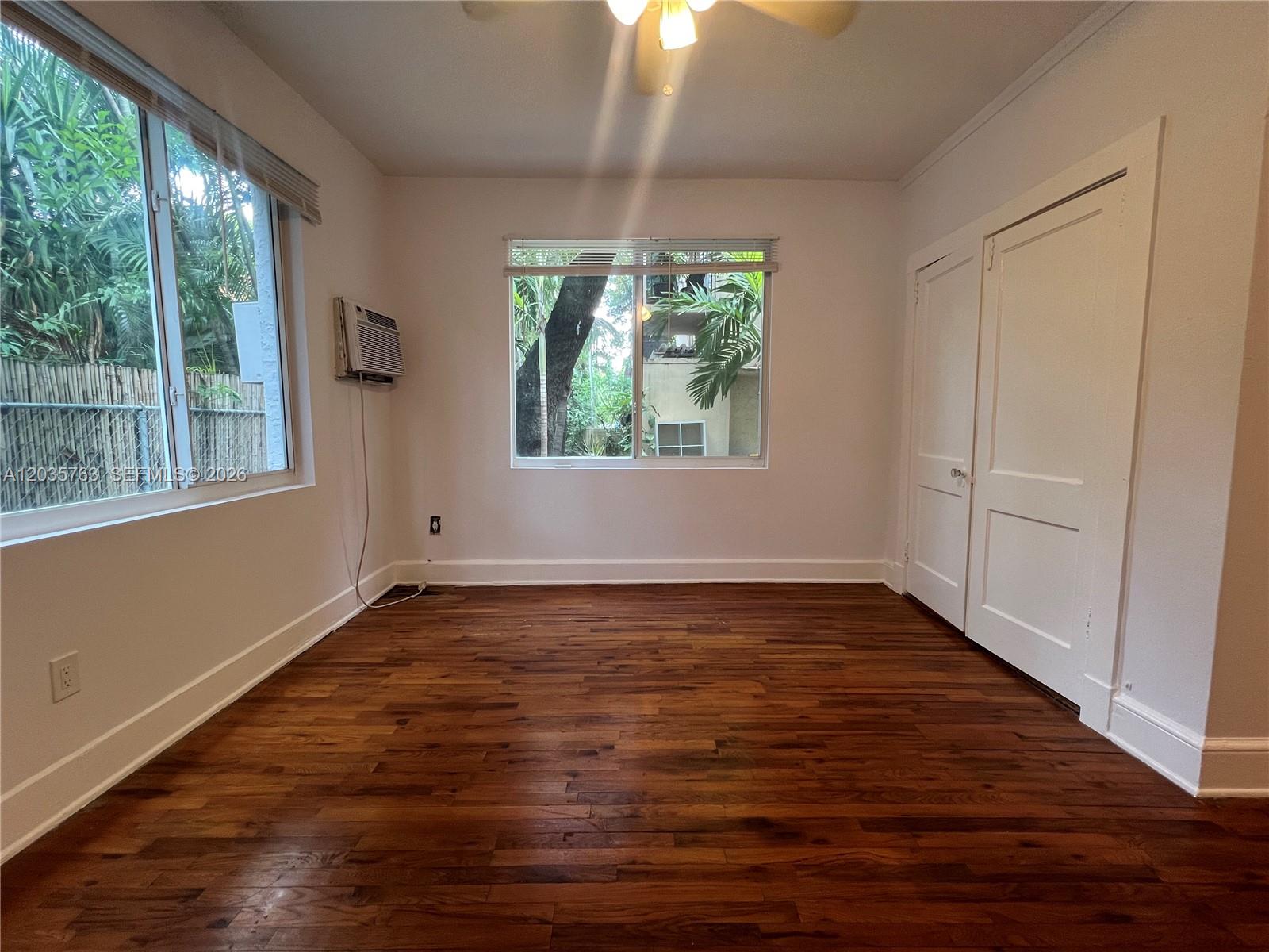 An empty bedroom features hardwood floors, white walls, two windows, and a double-door closet — 1610 Salzedo St # 5, Coral Gables FL 33134, CORAL GABLES, FL