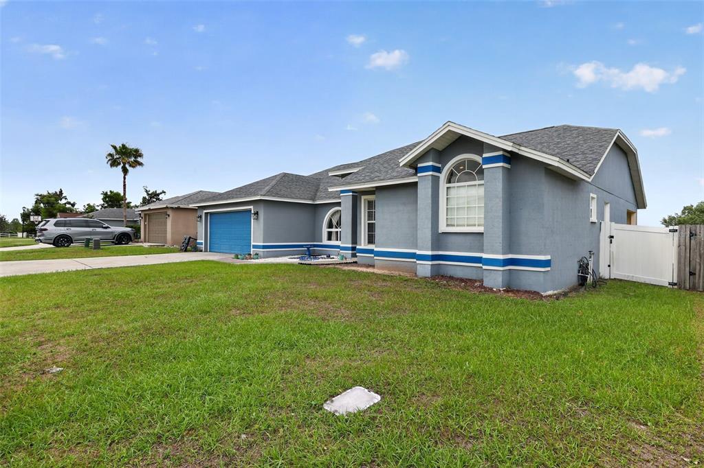 A single-story house with a gray exterior, blue accents, a two-car garage, and a lawn — 7938 ASHLEY POINTE DRIVE, LAKELAND, FL