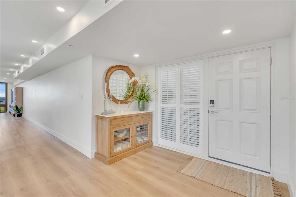 A bright entryway features light wood flooring, a wooden console table, and a white door — 5611 GULF OF MEXICO DRIVE UNIT 1, LONGBOAT KEY, FL