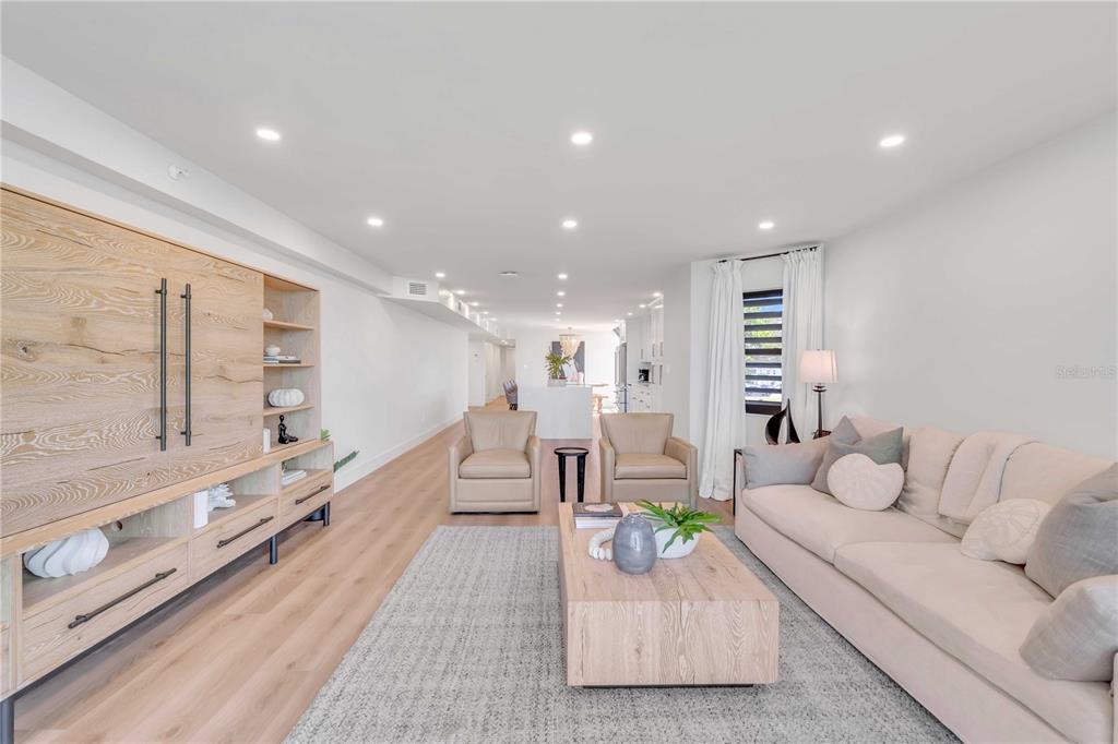A modern living room features light wood flooring, a large entertainment unit, and neutral furniture — 5611 GULF OF MEXICO DRIVE UNIT 1, LONGBOAT KEY, FL