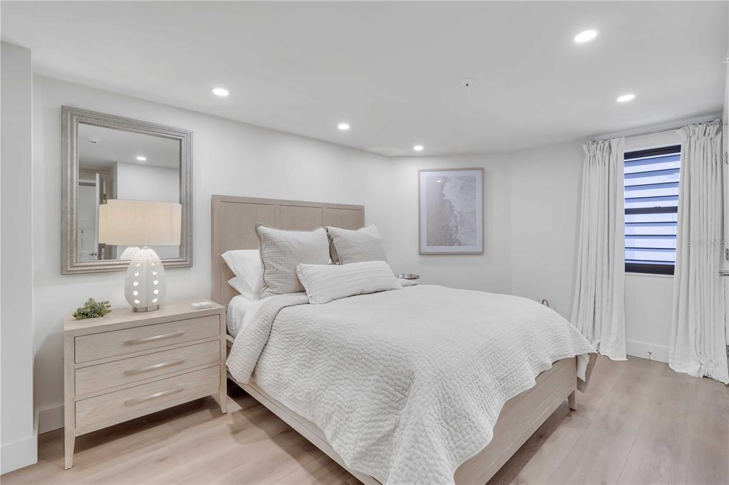 A bedroom features a light wood bed frame, a matching dresser, and white bedding — 5611 GULF OF MEXICO DRIVE UNIT 1, LONGBOAT KEY, FL