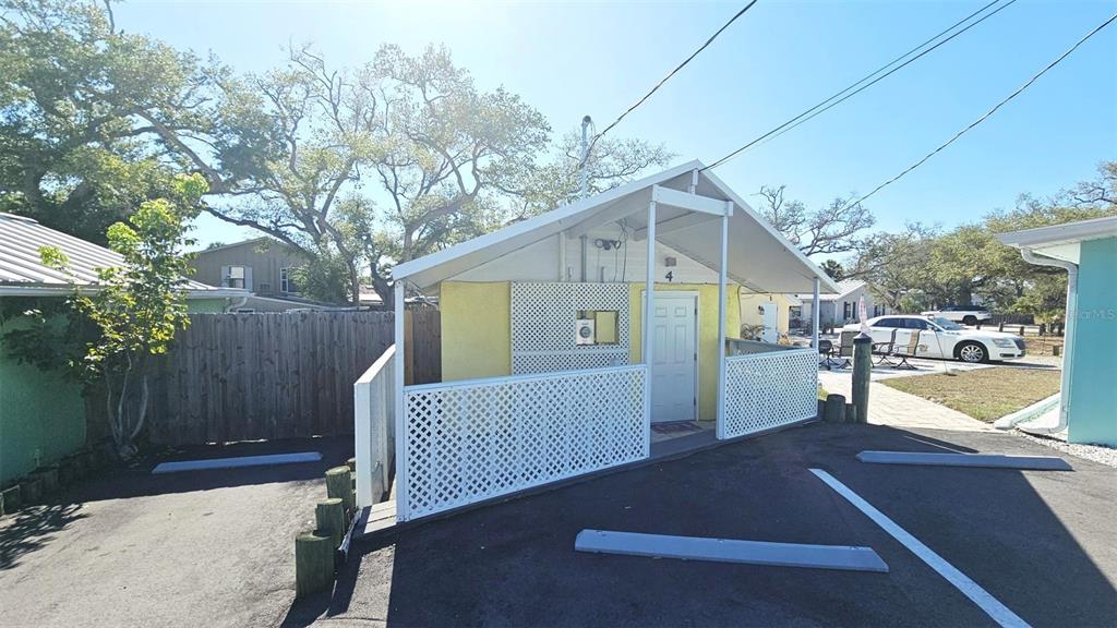 A small, yellow, single-story building with a white lattice porch and a white door — 870 S MCCALL ROAD UNIT 4, ENGLEWOOD, FL