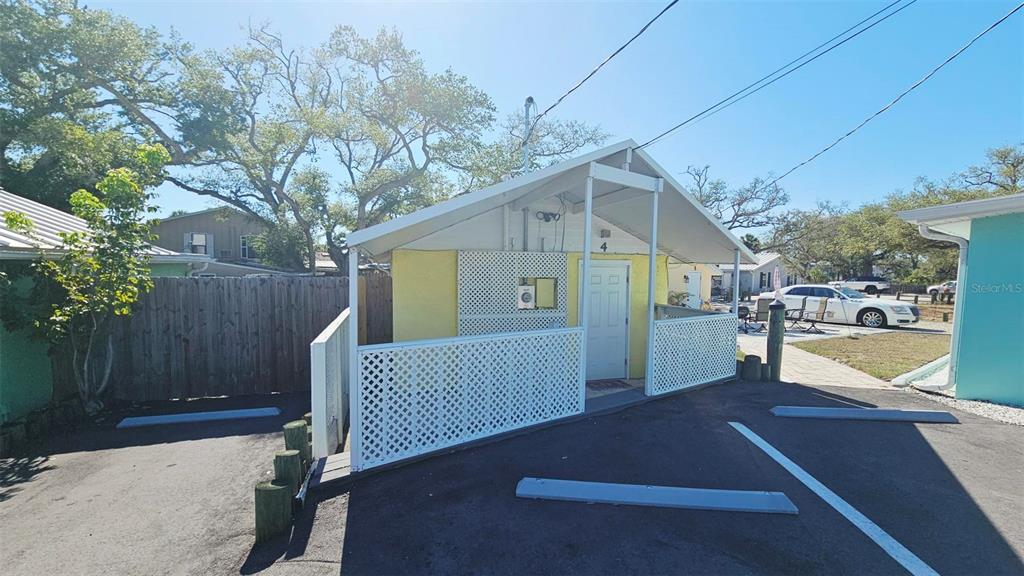 A small yellow building with a white lattice porch and a paved parking area — 870 S MCCALL ROAD UNIT 4, ENGLEWOOD, FL