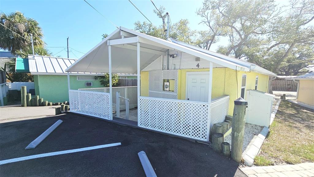 A yellow cottage with a white lattice-enclosed porch and a metal roof — 870 S MCCALL ROAD UNIT 4, ENGLEWOOD, FL