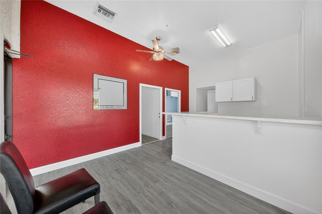 A room with a red accent wall, gray wood-look flooring, and a white breakfast bar — 595 9TH STREET, WINTER GARDEN, FL