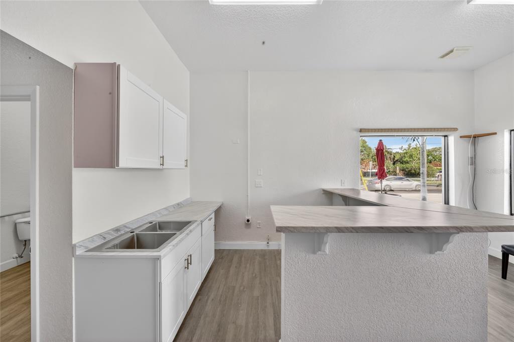 A kitchen area features white cabinets, a double sink, wood-look flooring, and a breakfast bar — 595 9TH STREET, WINTER GARDEN, FL