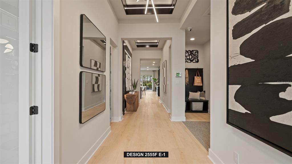 A modern hallway features light wood floors, two stacked mirrors, and a black-and-white abstract painting — 314 HOLLY BANK AVENUE, NOKOMIS, FL