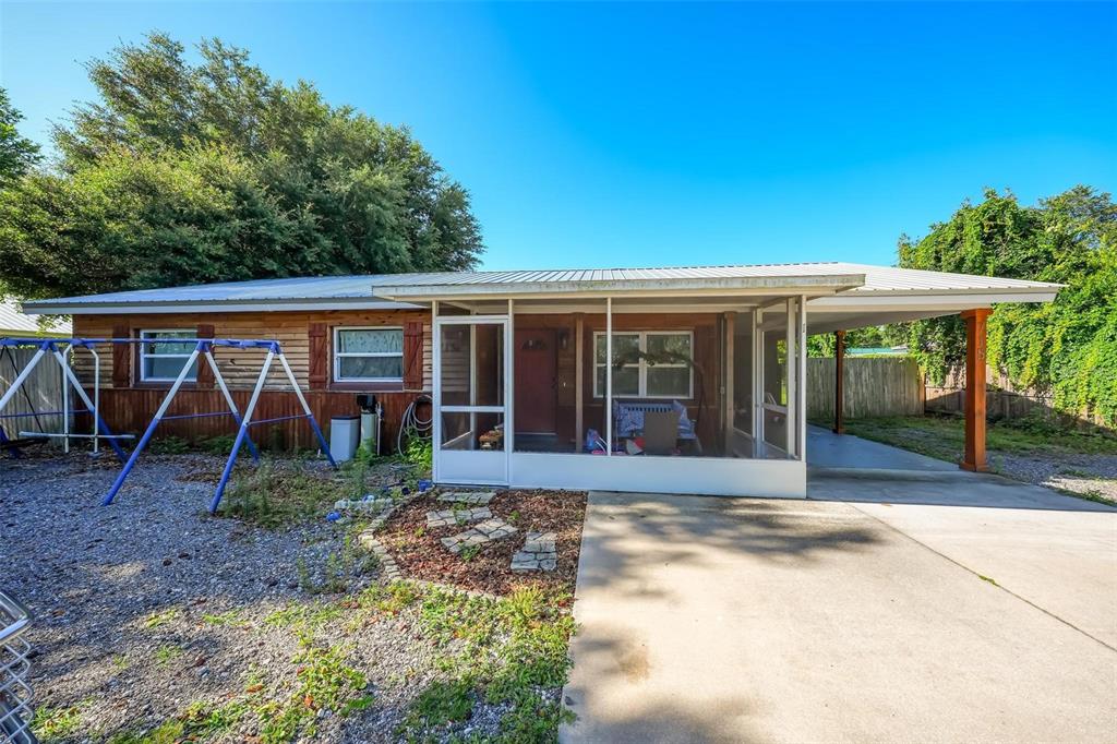 A single-story house with wood siding, a screened-in front porch, and an attached carport — 715 4TH STREET, POLK CITY, FL