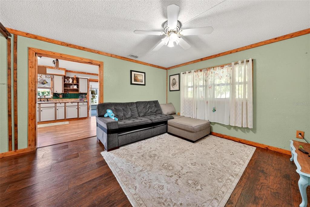 A living room features green walls, wood trim, a gray sectional, and a ceiling fan — 715 4TH STREET, POLK CITY, FL