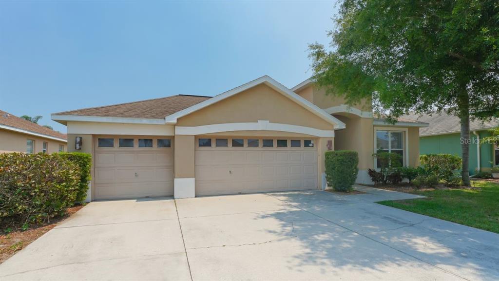 A tan single-story house with a three-car garage and a concrete driveway — 5453 NEW COVINGTON DRIVE, SARASOTA, FL
