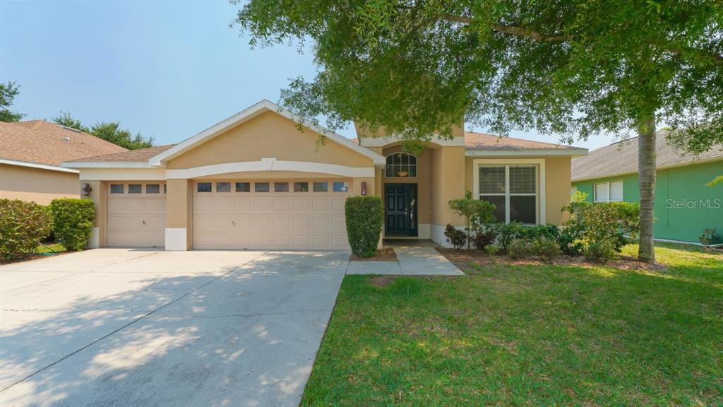 A single-story suburban house with a tan stucco exterior, a two-car garage, and a driveway — 5453 NEW COVINGTON DRIVE, SARASOTA, FL