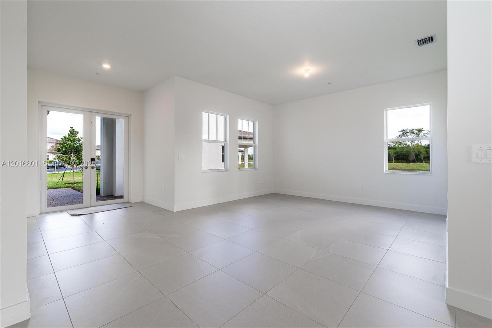 An empty room features white walls, large light-colored floor tiles, and glass patio doors — 4480 SW 122nd Ter # 0, Davie FL 33330, DAVIE, FL