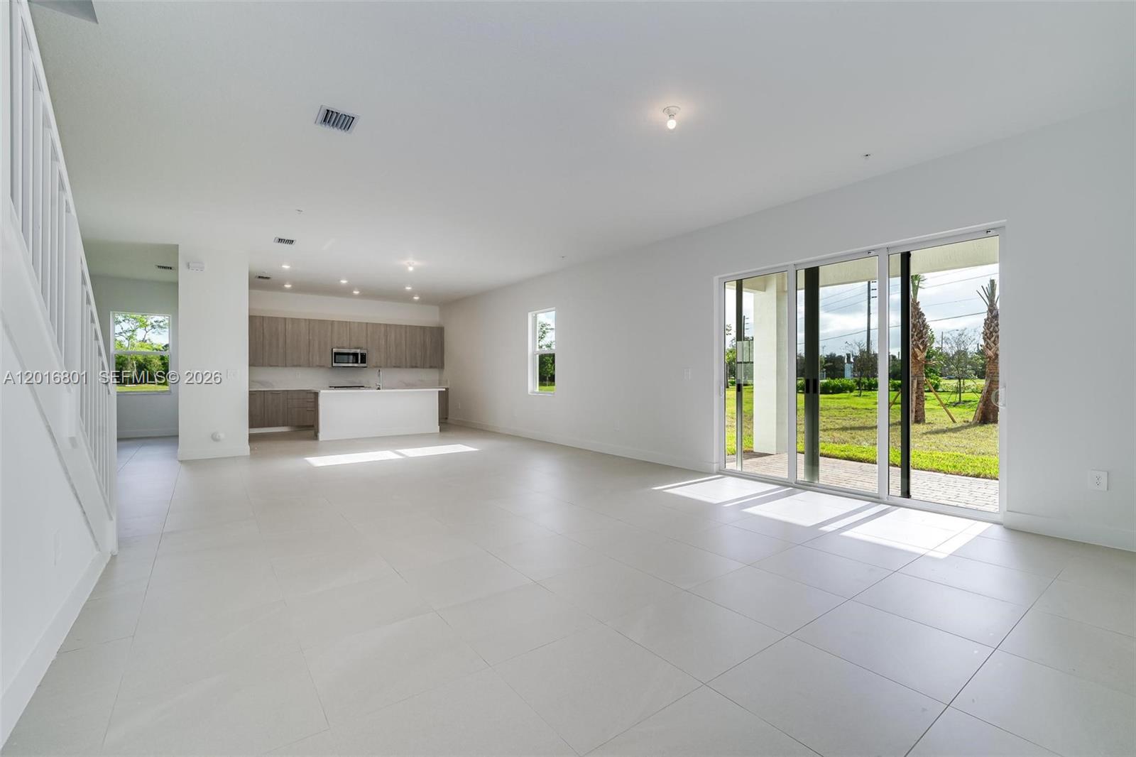 An open-concept living area features light tile floors, a modern kitchen, and sliding glass doors — 4480 SW 122nd Ter # 0, Davie FL 33330, DAVIE, FL
