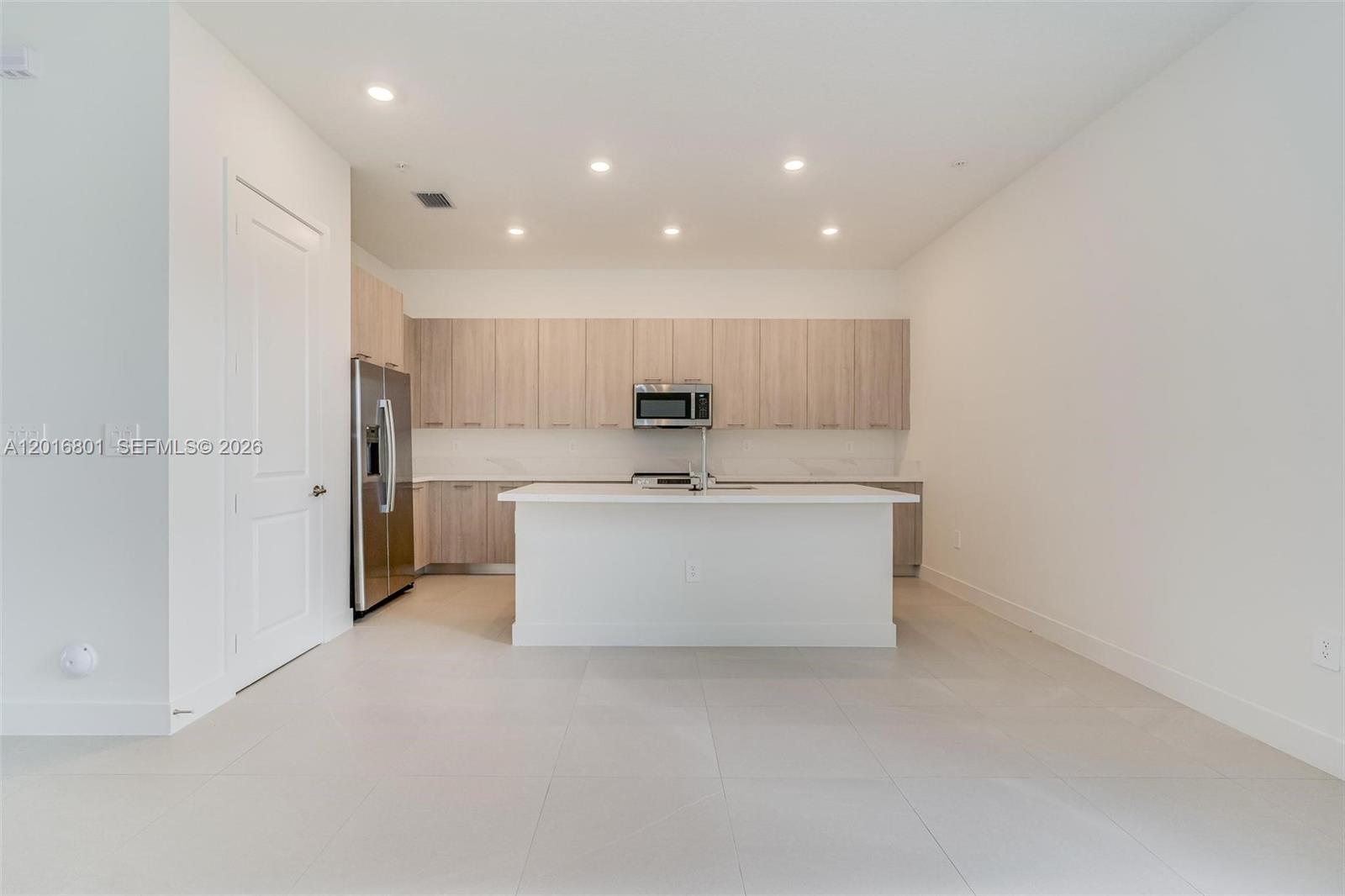 A modern kitchen features light wood cabinetry, a white island, and stainless steel appliances — 4480 SW 122nd Ter # 0, Davie FL 33330, DAVIE, FL