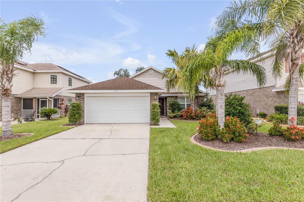 A single-story house with a white garage door, a concrete driveway, and palm trees — 5410 CORDGRASS BEND LANE, PORT ORANGE, FL