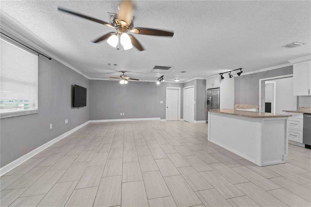 An open-concept living room and kitchen with gray walls, tile flooring, and two ceiling fans — 6290 PIEDMONT DRIVE, SPRING HILL, FL