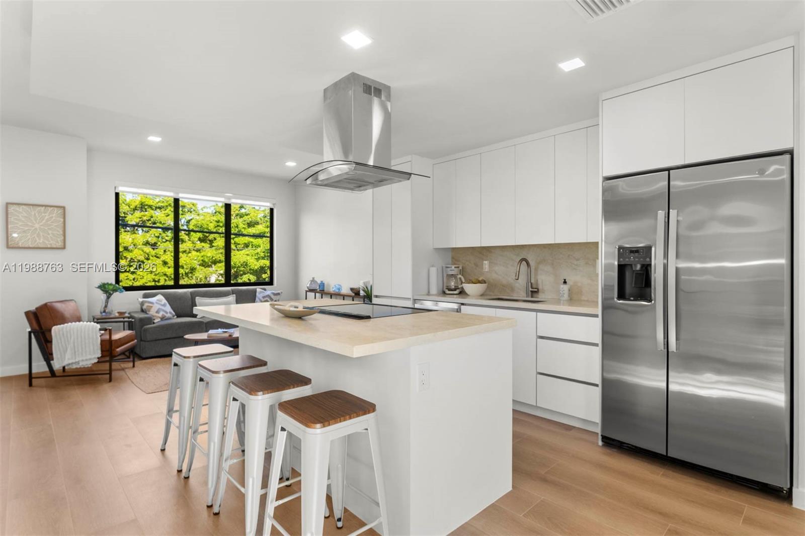 A modern kitchen features white cabinetry, a central island with bar stools, and stainless appliances — 1376 SW 4th St # 7, Miami FL 33135, MIAMI, FL