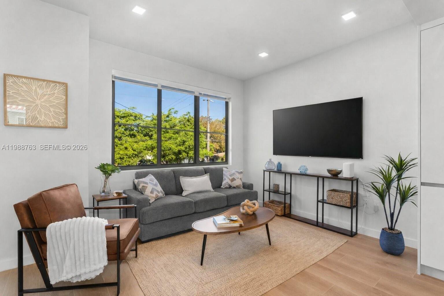 A living room features a grey sofa, a brown leather chair, and a wall-mounted television — 1376 SW 4th St # 7, Miami FL 33135, MIAMI, FL