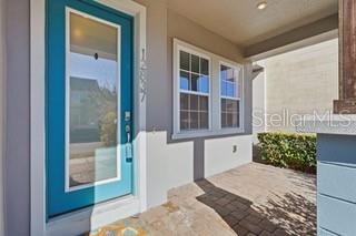 A bright blue front door opens onto a paved porch with a windowed exterior wall — 12837 SALK WAY, ORLANDO, FL