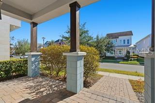 A covered porch with stone pillars overlooks a suburban street and neighboring houses — 12837 SALK WAY, ORLANDO, FL