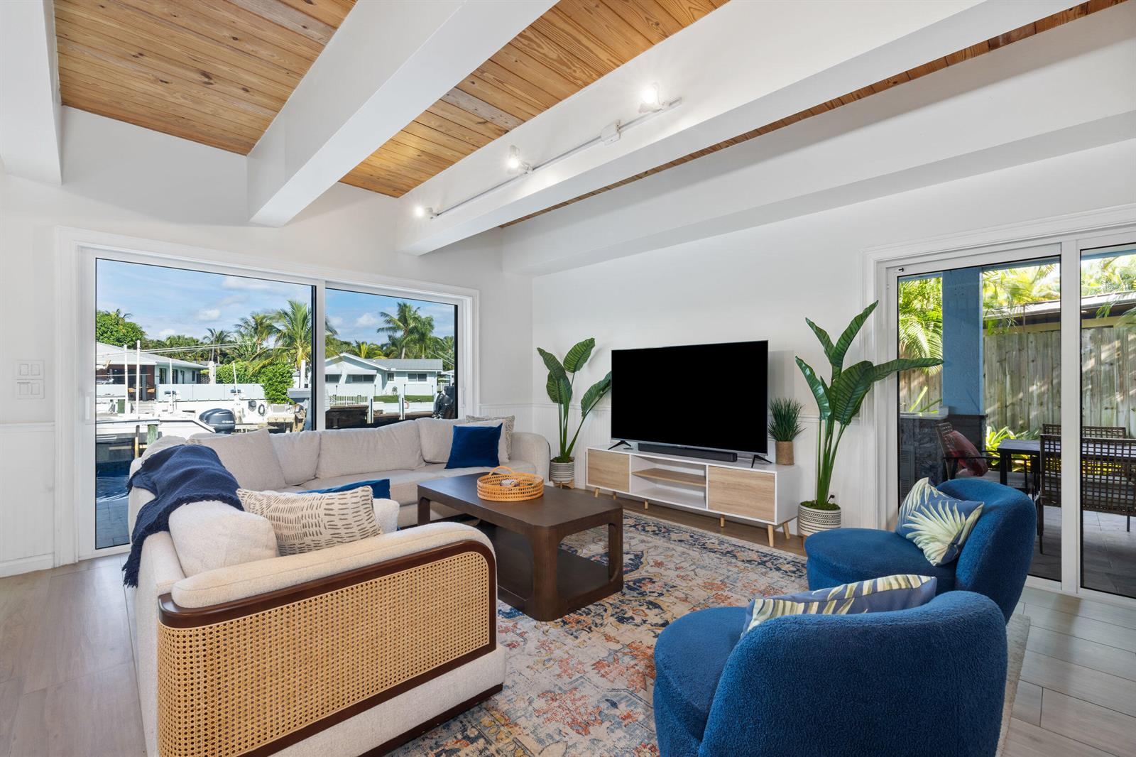 A living room features a sectional sofa, two blue chairs, and a view of boats — 100 Neptune Drive, Hypoluxo FL 33462, HYPOLUXO, FL