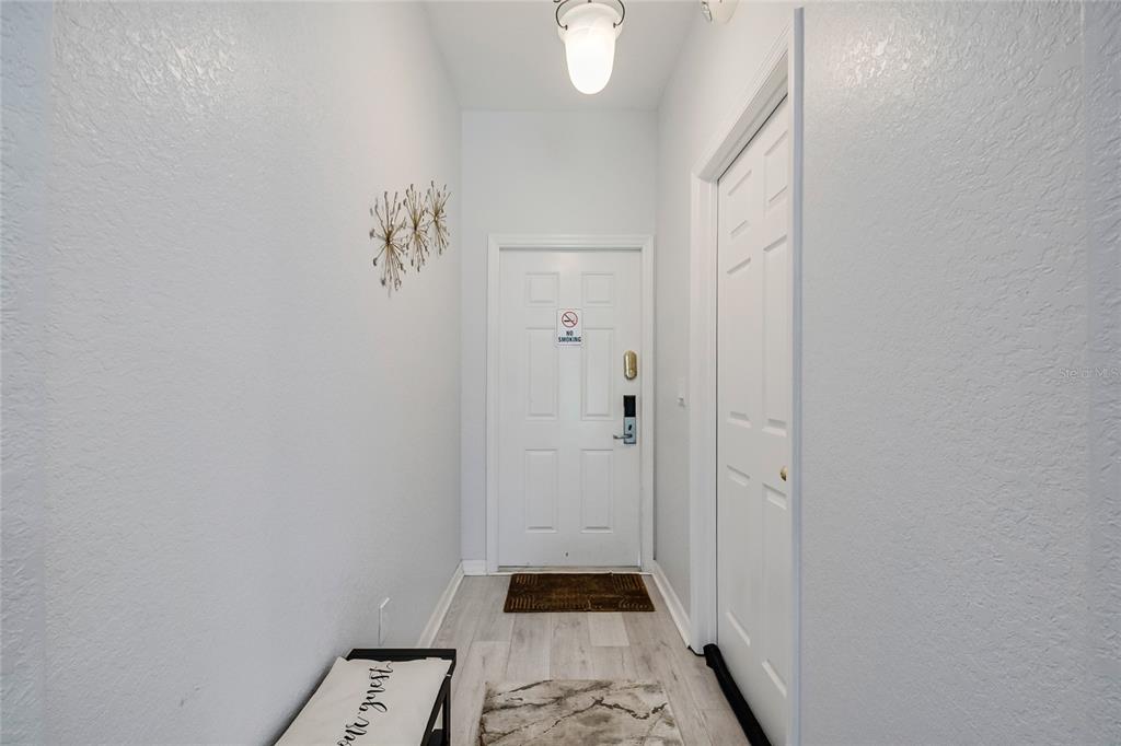 A narrow entryway features light wood-look flooring, white walls, a bench, and a front door — 226 BERGAMO DRIVE, DAVENPORT, FL