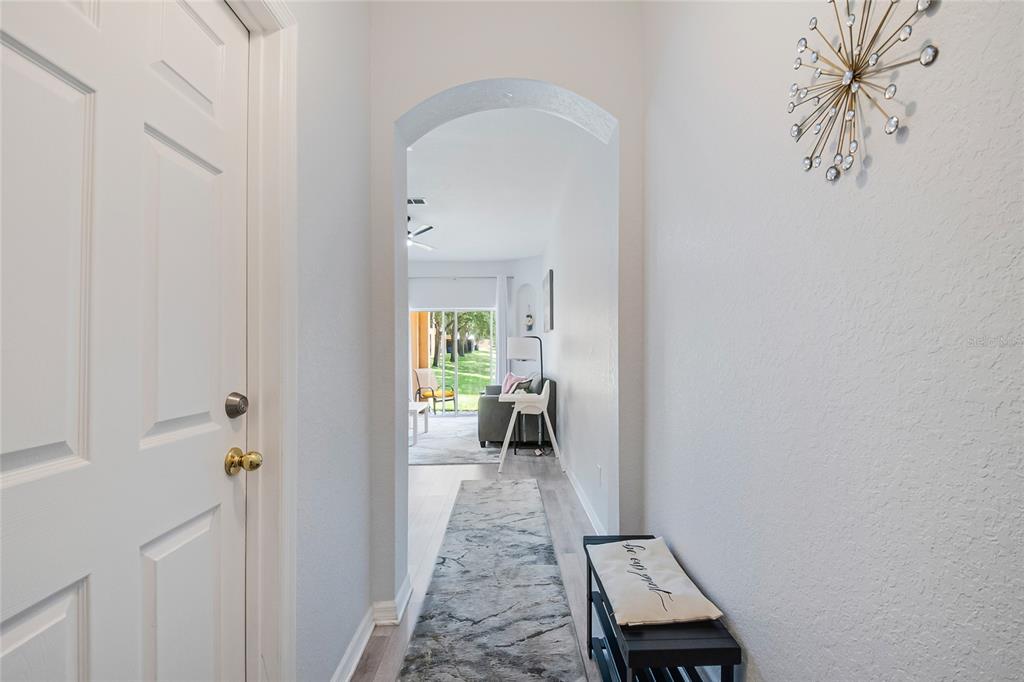 A hallway with a white door, a gray runner rug, and an arched entryway — 226 BERGAMO DRIVE, DAVENPORT, FL