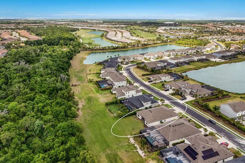 An aerial view shows a single-family home with a backyard bordering a dense forest — 4528 POND BROOK COURT, BRADENTON, FL