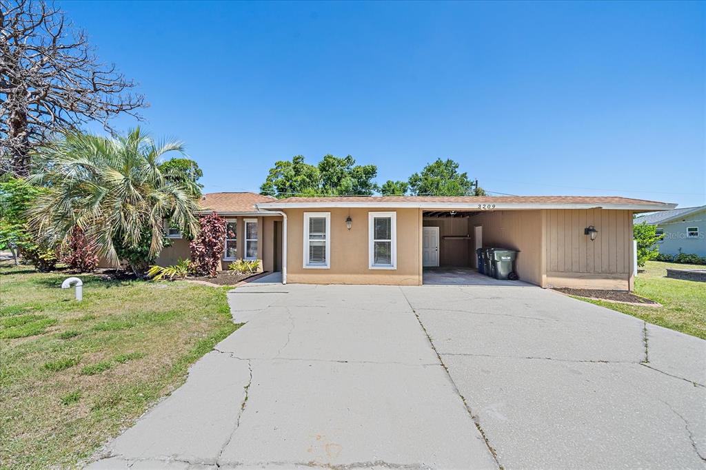 A single-story house with a tan exterior, a concrete driveway, and a covered carport — 3209 ASHTON ROAD, SARASOTA, FL