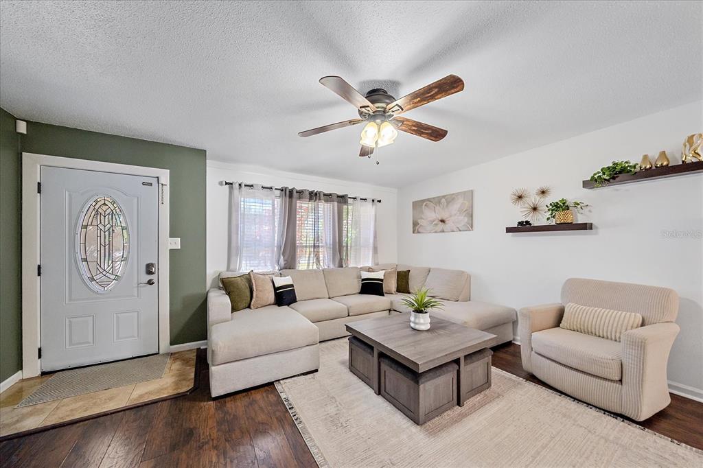 A living room features a sectional sofa, an armchair, a coffee table, and wood flooring — 3209 ASHTON ROAD, SARASOTA, FL