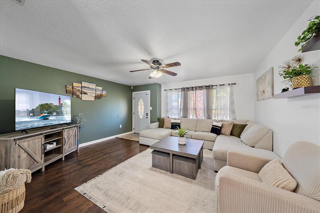 A living room features a green accent wall, a sectional sofa, and a television console — 3209 ASHTON ROAD, SARASOTA, FL