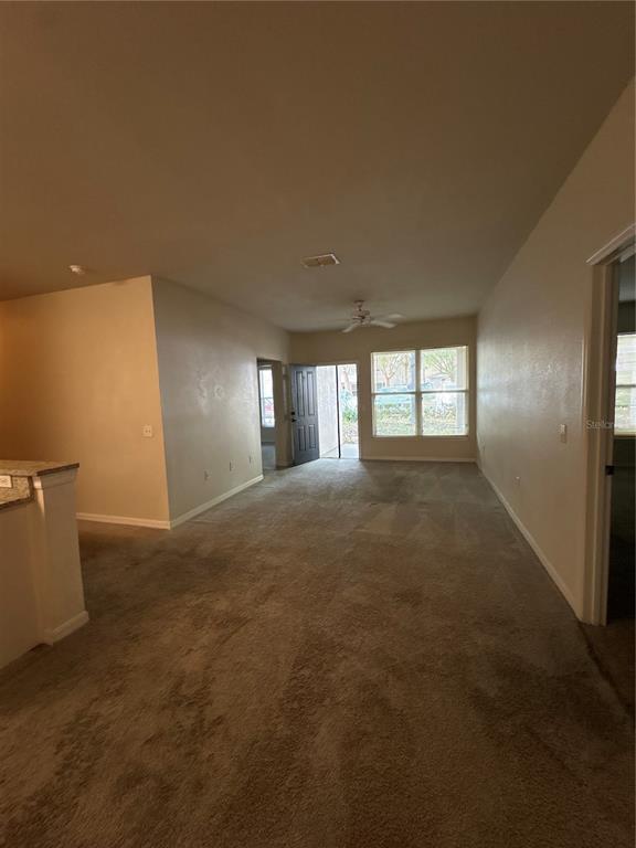 An interior view of a carpeted living area with a ceiling fan and exterior door — 8009 HEMINGWAY CIRCLE UNIT 8009, HAINES CITY, FL