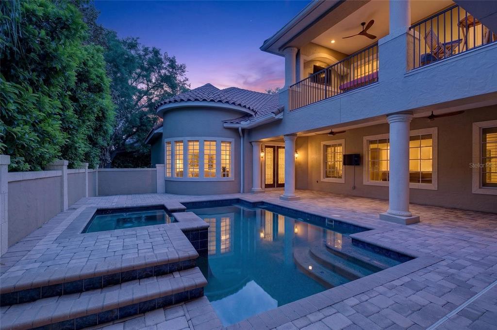 A two-story house exterior features a swimming pool, a spa, and a paved patio area — 11226 MACAW COURT, WINDERMERE, FL
