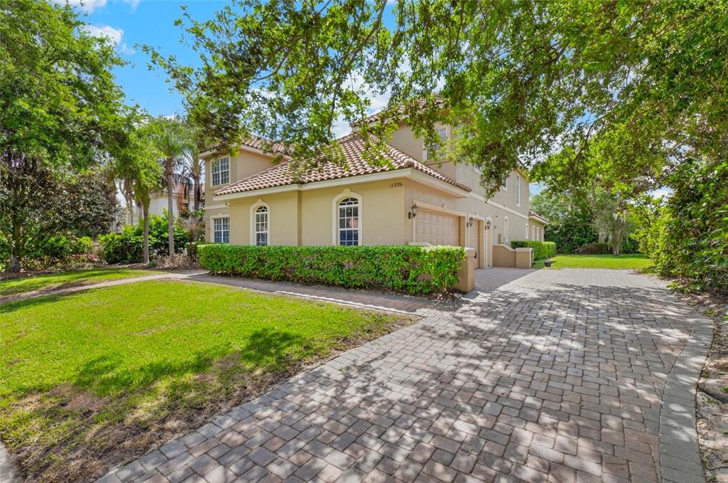 A two-story house with a tan stucco exterior, tile roof, and a brick paver driveway — 11226 MACAW COURT, WINDERMERE, FL