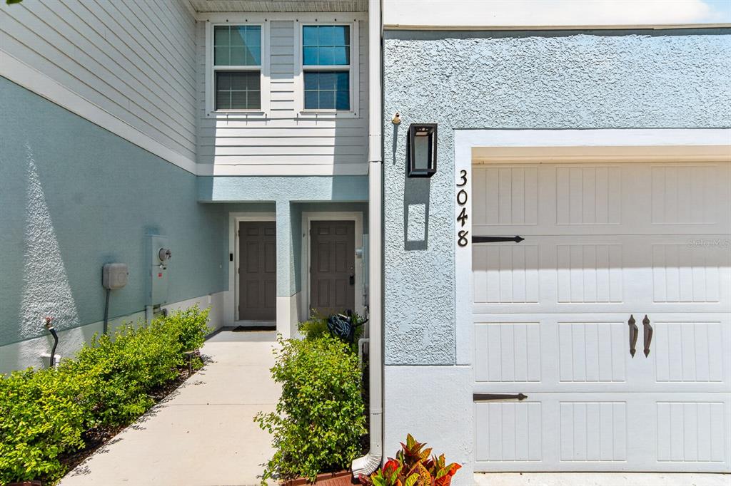 The exterior of a two-story townhouse features a white garage door and two front doors — 3048 VICTORIA INLET DRIVE, HOLIDAY, FL