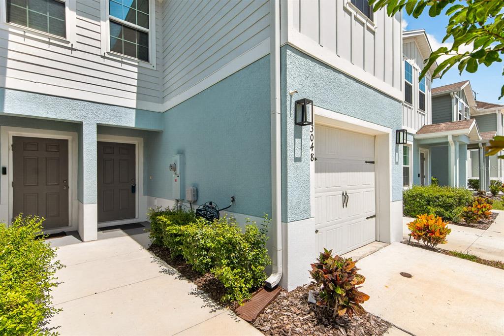 A light blue two-story townhouse exterior features a single-car garage and two front doors — 3048 VICTORIA INLET DRIVE, HOLIDAY, FL