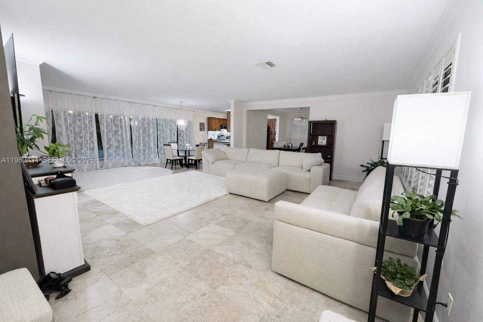 A spacious living room features light tile flooring, white sofas, and large floor-to-ceiling windows — 13451 SW 74th Ave, Pinecrest FL 33156, PINECREST, FL