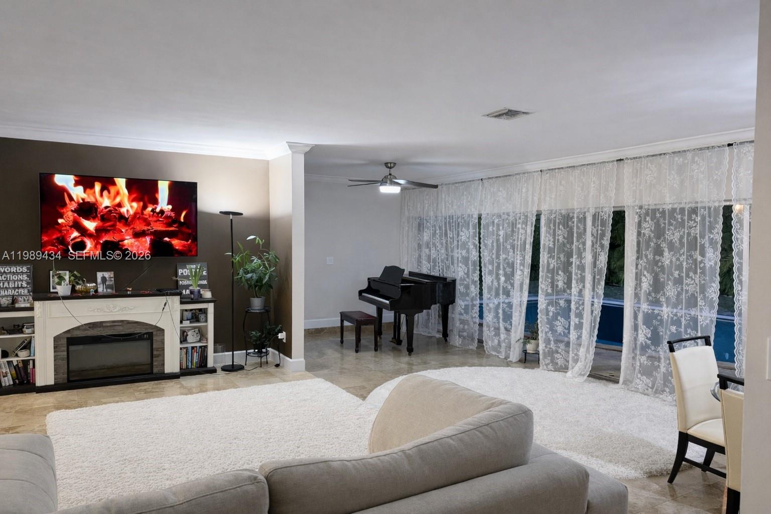 A living room features a fireplace, a grand piano, and large windows with lace curtains — 13451 SW 74th Ave, Pinecrest FL 33156, PINECREST, FL