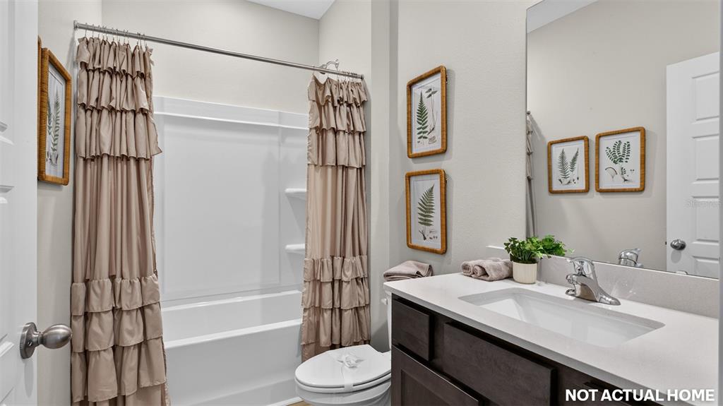 This bathroom features a vanity with a dark cabinet, a tub-shower combo, and framed artwork — 12 SAWDUST LANE, PALM COAST, FL
