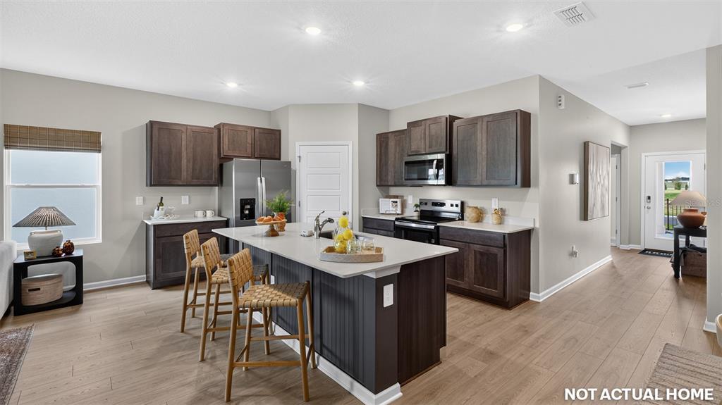 This kitchen features dark wood cabinets, a central island with bar stools, and light flooring — 12 SAWDUST LANE, PALM COAST, FL