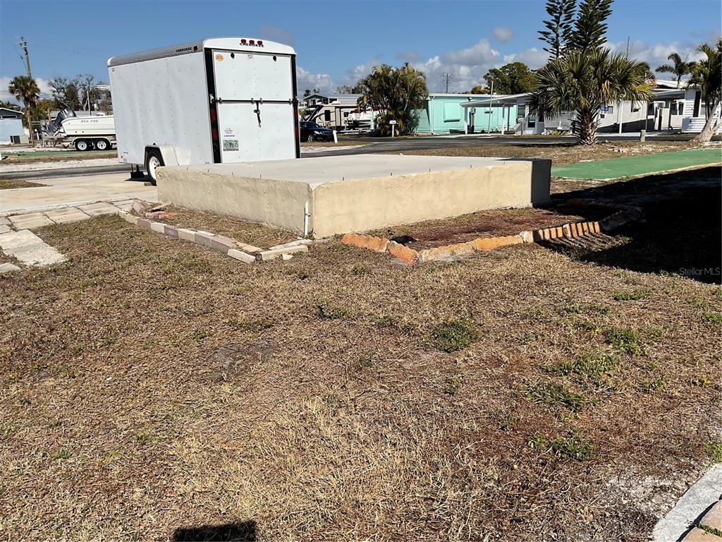 A concrete slab foundation sits on a grassy lot next to a white trailer — 165 MORNING STAR ROAD, VENICE, FL