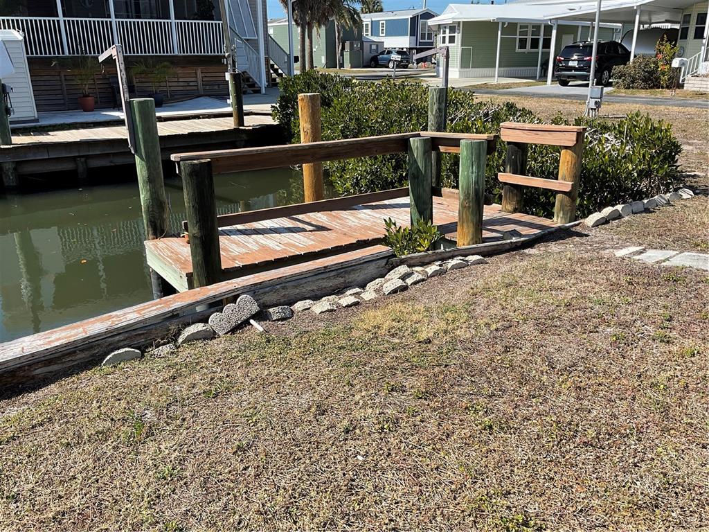 A wooden dock sits along a canal next to a grassy yard and residential homes — 165 MORNING STAR ROAD, VENICE, FL