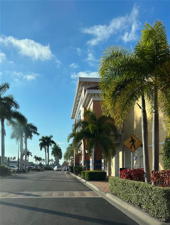 A paved road leads past a commercial building with palm trees and a pedestrian sign — 486 DAILEY STREET, PORT CHARLOTTE, FL